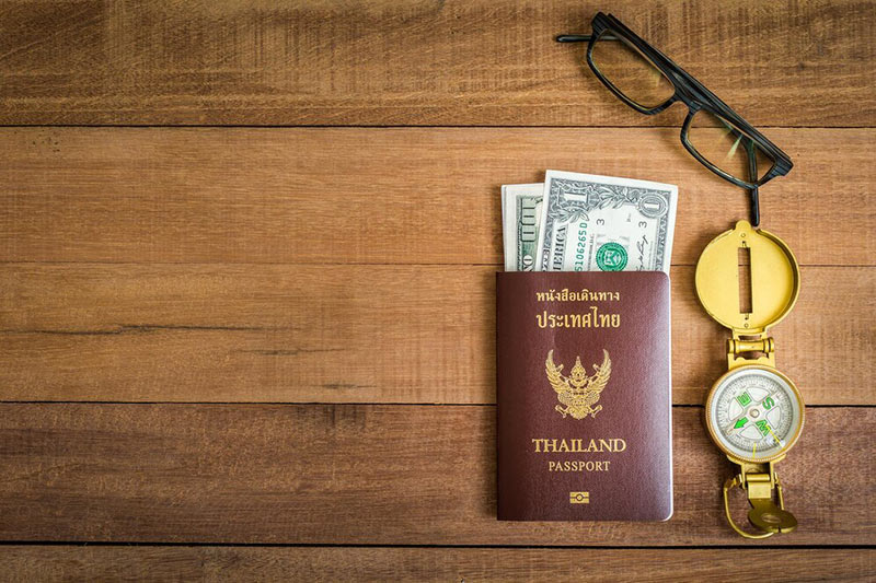 eyeglasses with navigational compass by passport currency wooden table