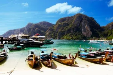 Long-tail boats anchored on a tropical beach at Phi Phi Islands, Thailand.
